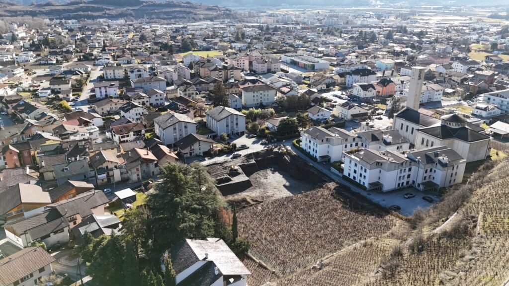 Luftaufnahme eines Wohngebiets mit Blick auf ein freies Grundstück