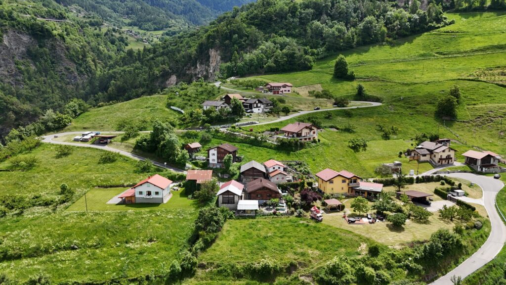 Luftaufnahme einer grünen Hangsiedlung mit verstreuten Häusern