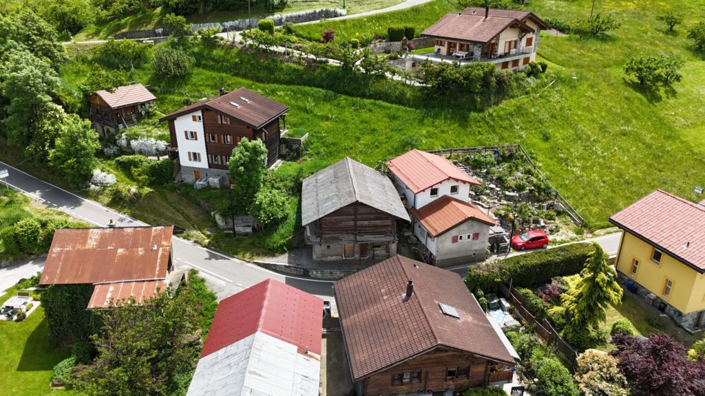 Luftaufnahme eines Dorfes in grüner Hanglage